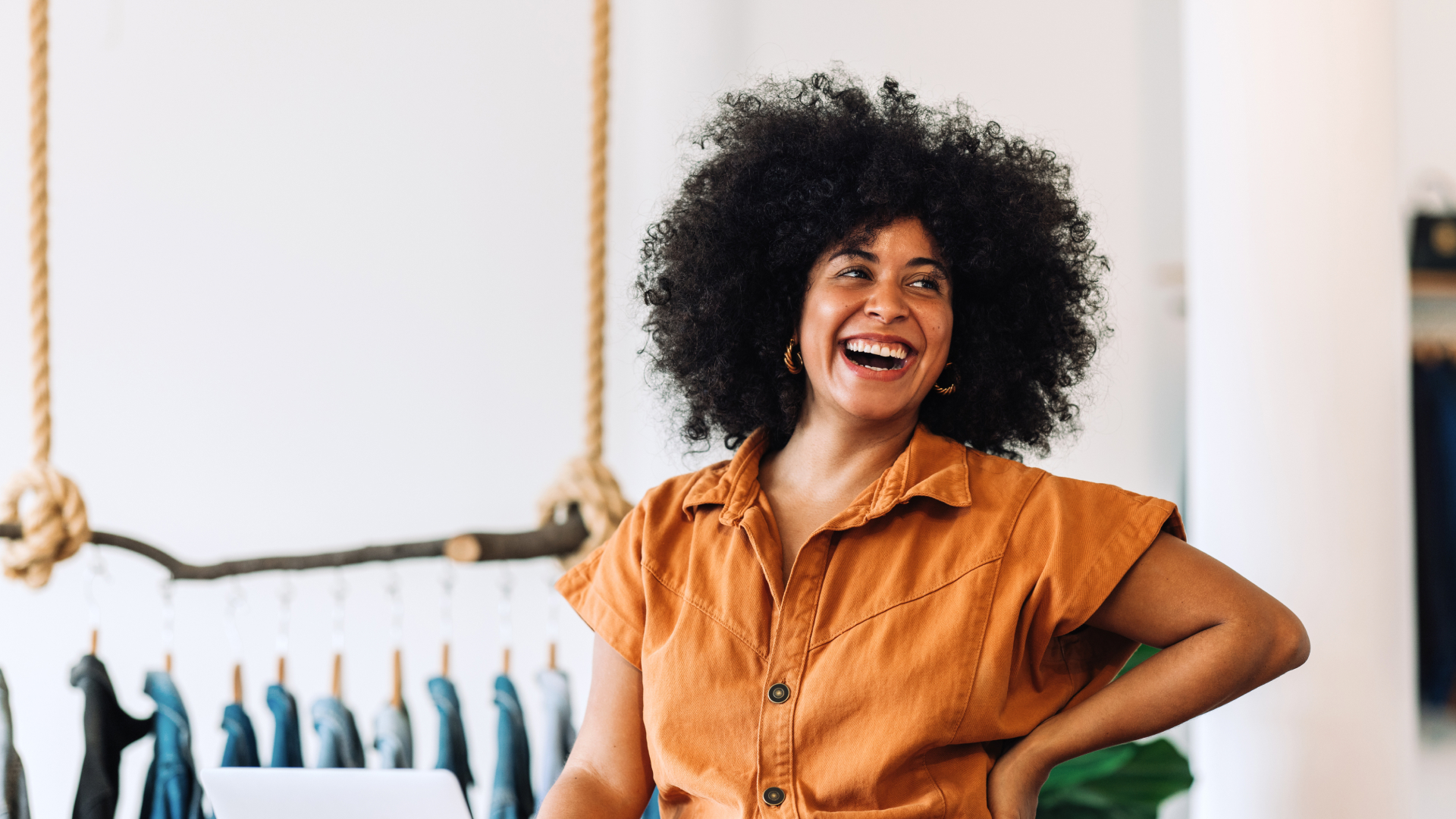  Smiling woman in a concept store in front of a laptop – representing entrepreneurial optimism in times of changing consumer behavior